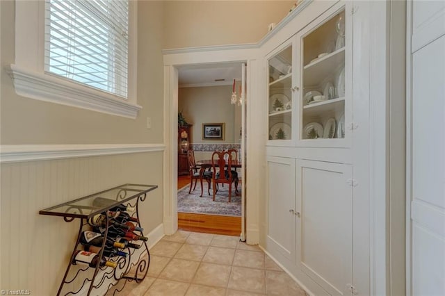 corridor featuring light tile patterned flooring and crown molding