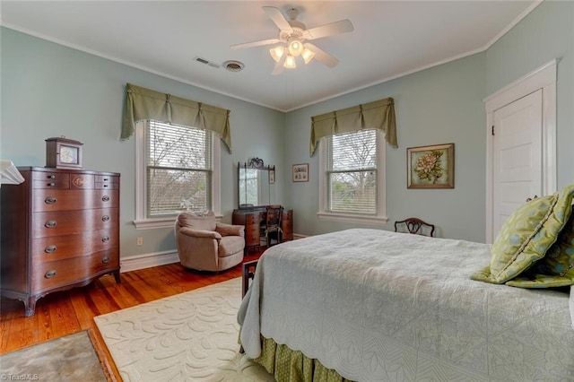 bedroom featuring hardwood / wood-style flooring, multiple windows, ornamental molding, and ceiling fan