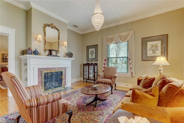 living room with crown molding, a fireplace, a chandelier, and light wood-type flooring