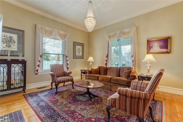 living room featuring hardwood / wood-style floors, ornamental molding, and an inviting chandelier