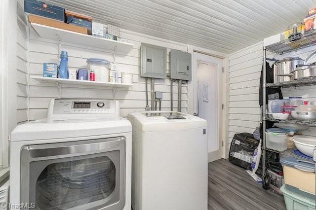 laundry room featuring wood walls, electric panel, dark wood-type flooring, and washing machine and clothes dryer