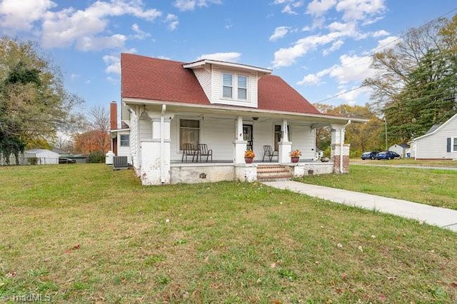 view of front of property featuring cooling unit, a porch, and a front lawn