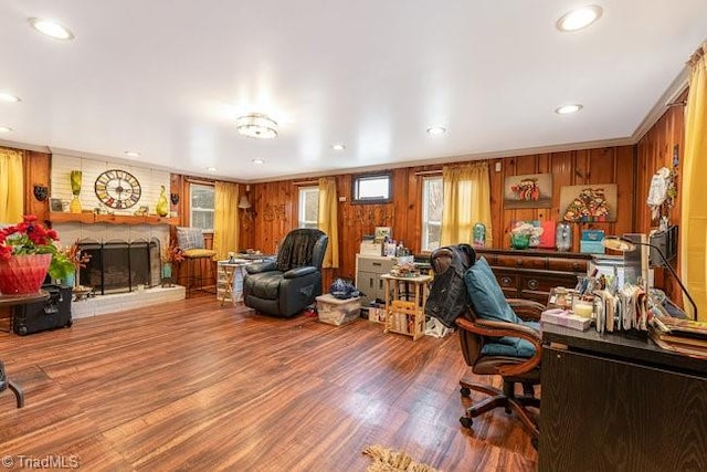 home office with wood-type flooring, crown molding, wooden walls, and a brick fireplace