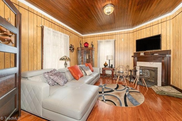 living room with crown molding, wooden walls, hardwood / wood-style flooring, a fireplace, and wood ceiling