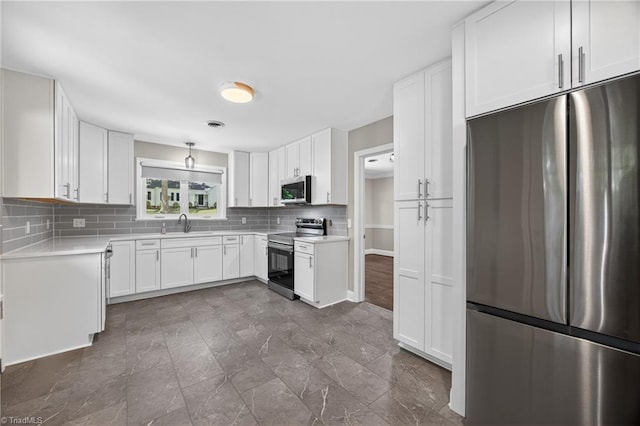 503 Tarleton Ave, Burlington, NC 27215 - kitchen with stainless steel appliances, decorative backsplash, light countertops, white cabinetry, and dark stone finish flooring