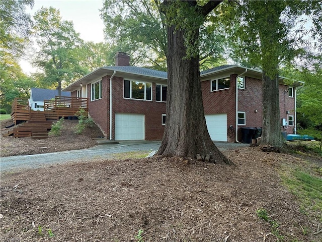 503 Tarleton Ave, Burlington, NC 27215 - view of front facade with a garage, brick siding, a chimney, driveway, and a deck