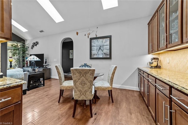 653 Piedmont Crossing Dr, High Point, NC 27265 - dining room featuring a skylight, arched walkways, wood finished floors, and vaulted ceiling