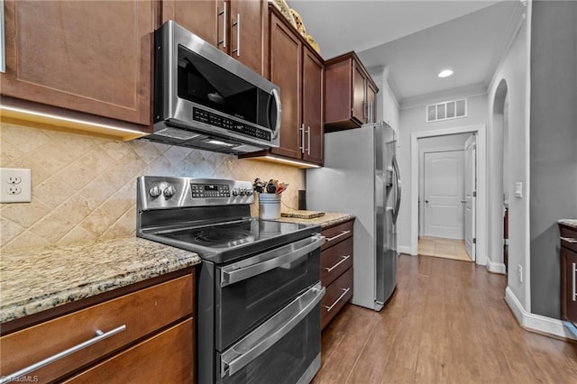 653 Piedmont Crossing Dr, High Point, NC 27265 - kitchen with appliances with stainless steel finishes, arched walkways, dark wood-type flooring, light stone countertops, and decorative backsplash