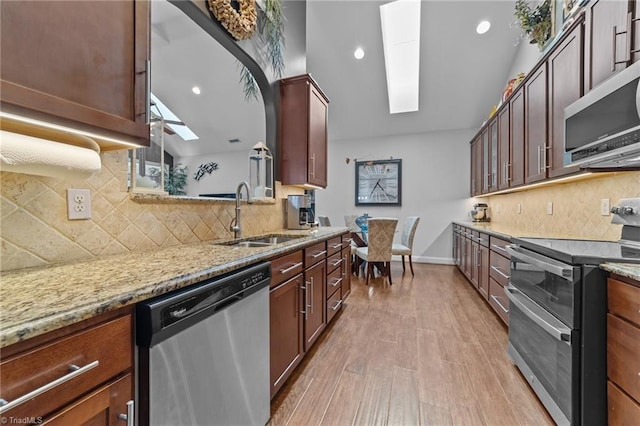 653 Piedmont Crossing Dr, High Point, NC 27265 - kitchen featuring appliances with stainless steel finishes, light stone countertops, decorative backsplash, light wood-style flooring, and a skylight