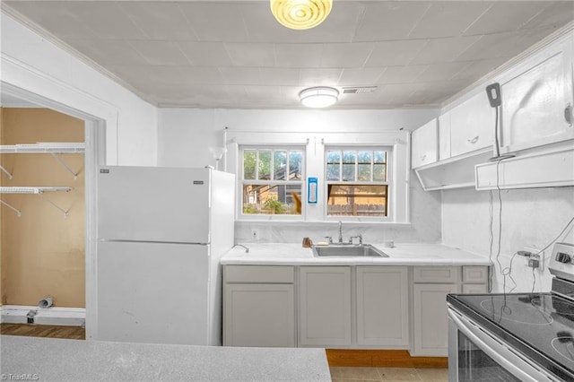 1821 Johnson St, High Point, NC 27262 - kitchen featuring stainless steel range with electric cooktop, a sink, light countertops, freestanding refrigerator, and visible vents