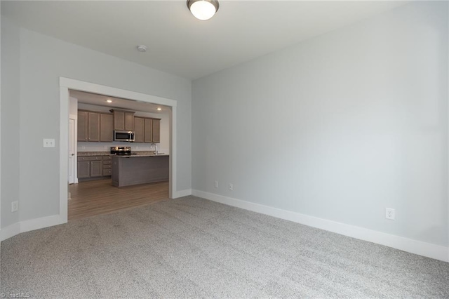 unfurnished living room with carpet flooring and baseboards