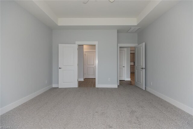 unfurnished bedroom with a tray ceiling, baseboards, and carpet flooring