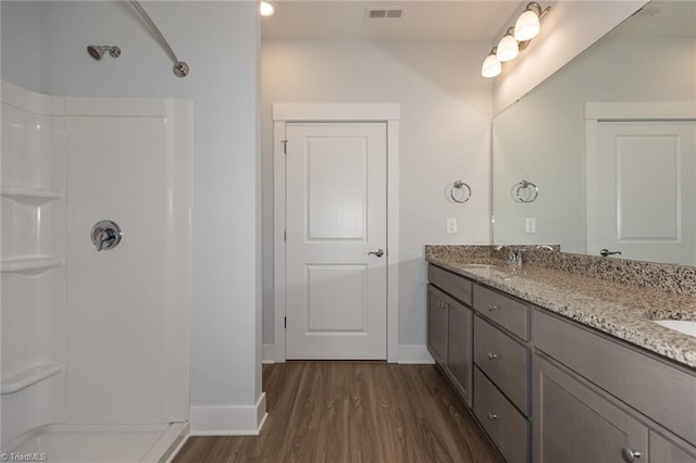 bathroom with a sink, visible vents, wood finished floors, and walk in shower