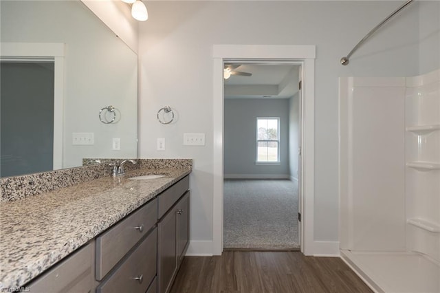 bathroom featuring baseboards, wood finished floors, vanity, and walk in shower