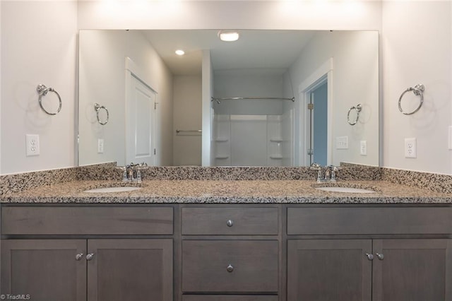 full bath featuring a shower, double vanity, and a sink