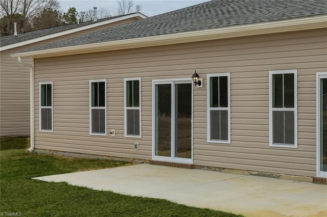 back of property with a lawn, a patio, and roof with shingles