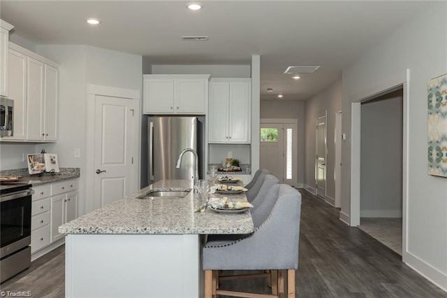 kitchen with recessed lighting, a sink, visible vents, light stone countertops, and appliances with stainless steel finishes