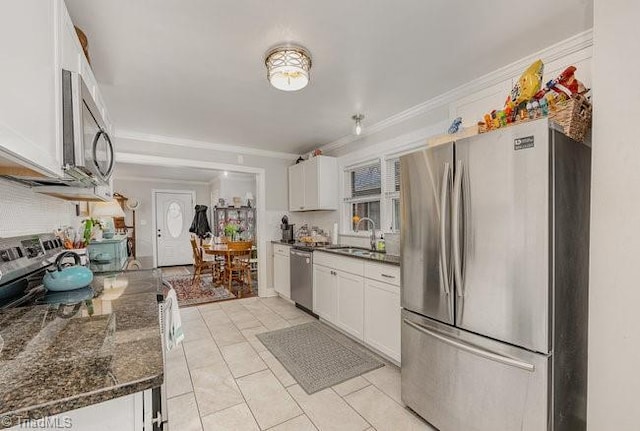 kitchen with white cabinetry, sink, dark stone counters, stainless steel appliances, and crown molding