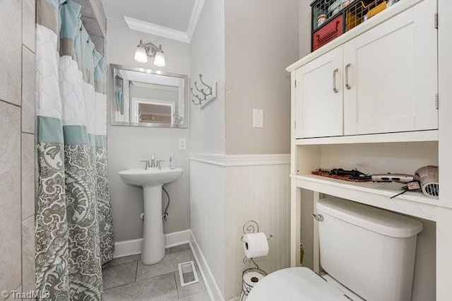 bathroom with crown molding, toilet, and tile patterned flooring