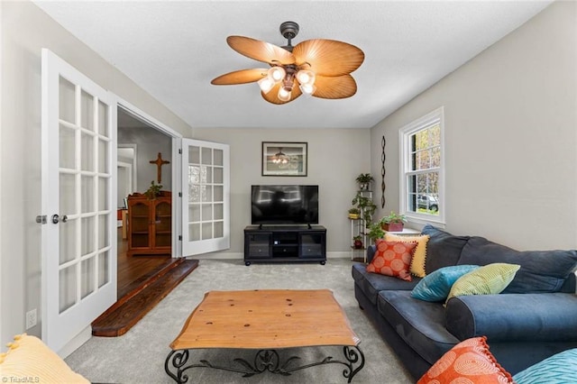 carpeted living area with a ceiling fan, french doors, and baseboards