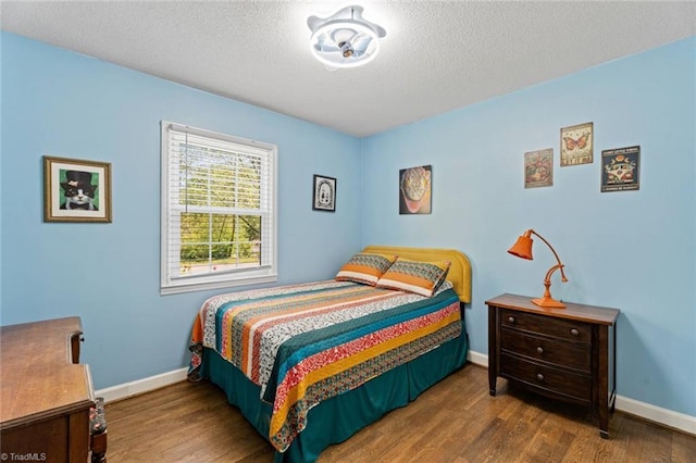bedroom with wood finished floors, baseboards, and a textured ceiling