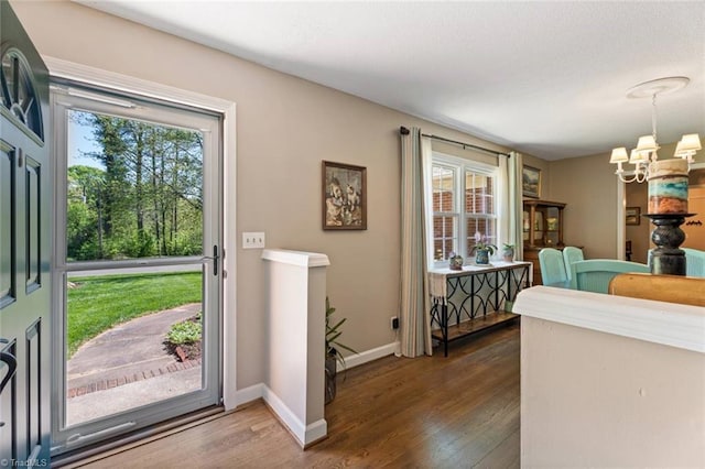 entrance foyer with a chandelier, wood finished floors, and baseboards