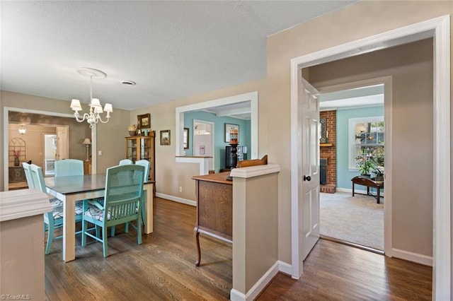 dining room featuring a chandelier, dark wood-style floors, baseboards, and a textured ceiling
