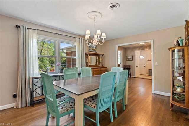 dining area featuring a chandelier, wood finished floors, baseboards, and a textured ceiling