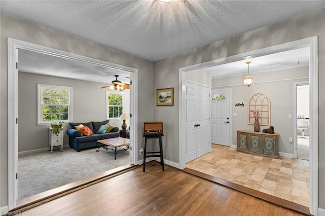 foyer entrance featuring wood finished floors, a textured ceiling, baseboards, and ceiling fan