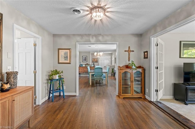 sitting room featuring dark wood finished floors, a chandelier, a textured ceiling, and baseboards