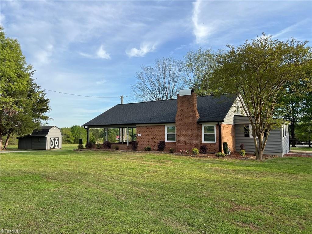 back of property featuring a lawn, an outdoor structure, a chimney, and a shed