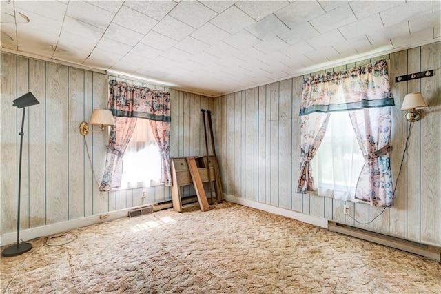 2405 Ellington St, Greensboro, NC 27403 - carpeted empty room featuring a baseboard heating unit and wood walls