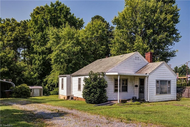 2405 Ellington St, Greensboro, NC 27403 - view of front of property featuring a storage shed, a chimney, a front lawn, and a shingled roof
