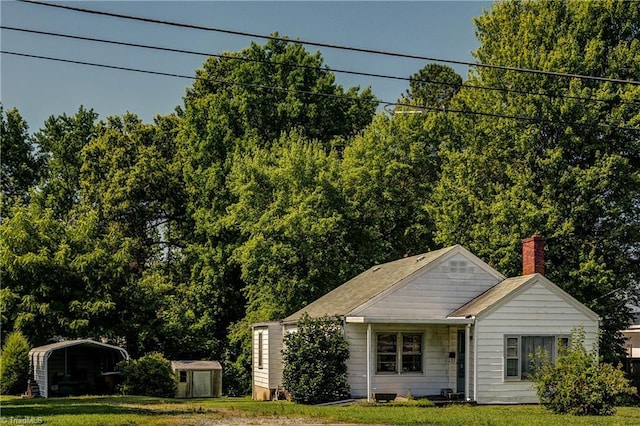2405 Ellington St, Greensboro, NC 27403 - view of front facade with a shed, a front yard, a chimney, and a carport