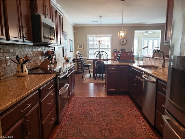 kitchen with appliances with stainless steel finishes, decorative light fixtures, sink, ornamental molding, and light stone countertops