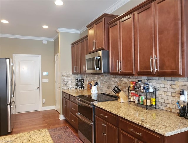 kitchen featuring appliances with stainless steel finishes, crown molding, light stone counters, and decorative backsplash