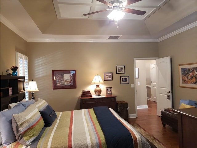 bedroom with baseboards, a tray ceiling, wood finished floors, and ornamental molding