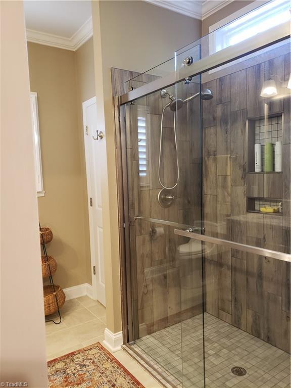 bathroom featuring an enclosed shower, crown molding, and tile patterned floors