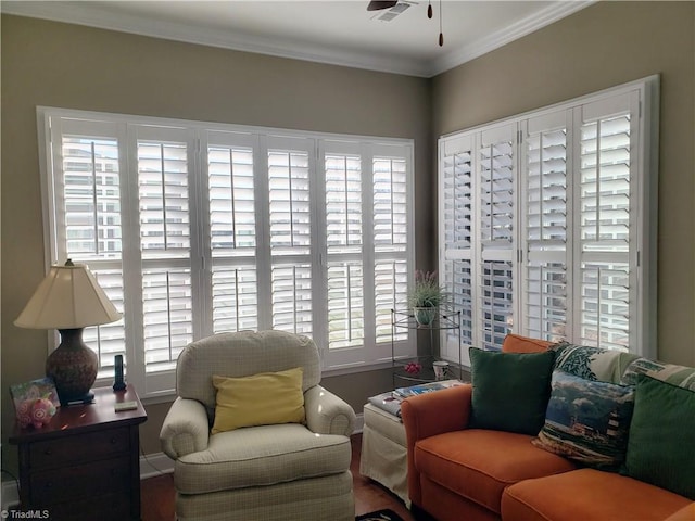 sitting room with a ceiling fan, baseboards, visible vents, and crown molding