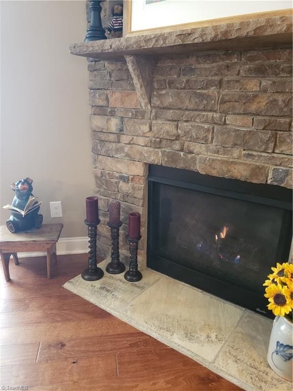 room details featuring a fireplace, baseboards, and wood finished floors