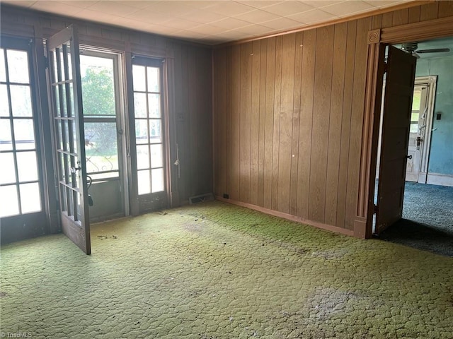 empty room with visible vents, carpet flooring, and wood walls