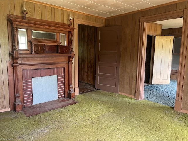 unfurnished living room featuring baseboards, carpet flooring, a brick fireplace, and wood walls