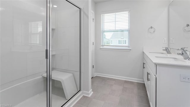 full bathroom featuring a sink, a stall shower, baseboards, and double vanity