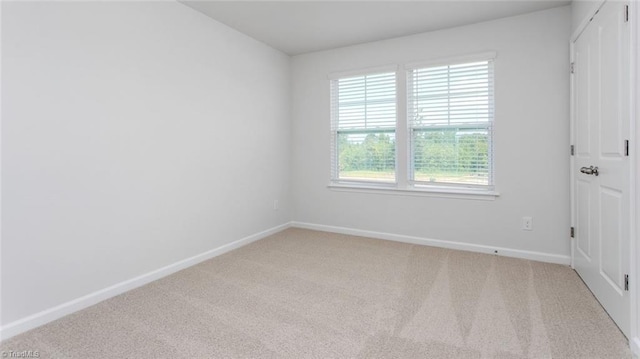 spare room featuring light colored carpet and baseboards