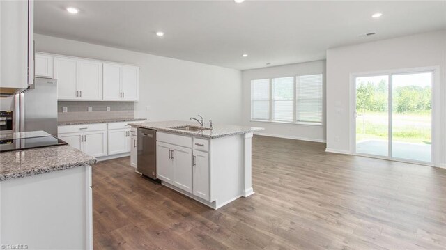 kitchen featuring sink, appliances with stainless steel finishes, wood-type flooring, white cabinetry, and a center island with sink