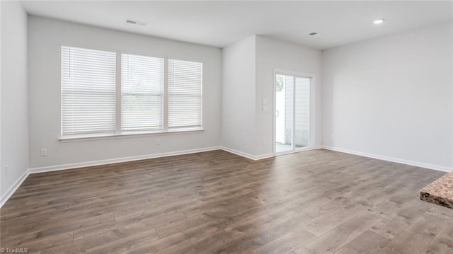 spare room featuring recessed lighting, wood finished floors, visible vents, and baseboards