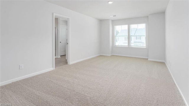 empty room featuring light colored carpet and baseboards