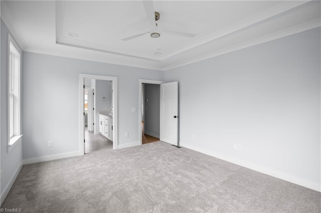 unfurnished bedroom with a raised ceiling, baseboards, a ceiling fan, and carpet flooring