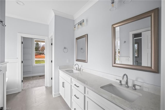 bathroom with double vanity, baseboards, ornamental molding, and a sink