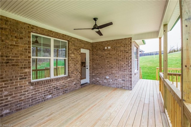 wooden terrace with a lawn and a ceiling fan